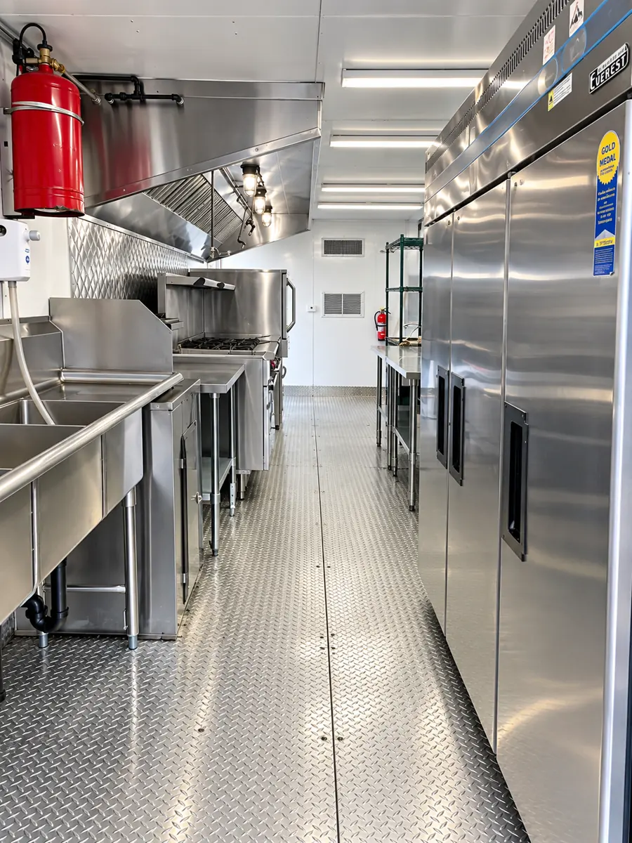 Stainless steel cooking line, sinks and refrigerators inside a mobile kitchen trailer
