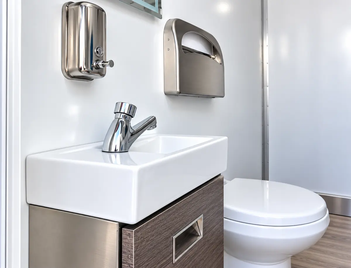 Sink with soap and paper towel dispensers in a restroom trailer
